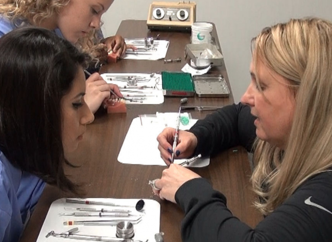 dental instructor showing proper cleaning technique to student