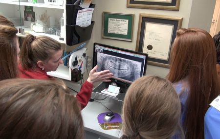 Dental instructor reviewing x-rays with dental assisting students,